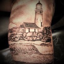 Costal Lighthouse with waves on the rocks - fine line black and grey tattoo created by tattoo artist Alan Lott, Co-founder and tattoo artist at Sacred Mandala Studio in Durham, North Carolina